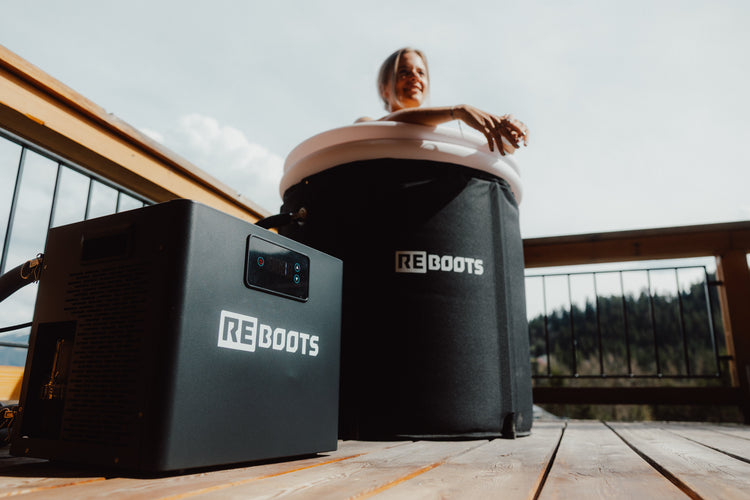 Frau genießt Kältebad im Reboots Ice Tub auf einer Sonnenterrasse – effektive Regeneration mit dem Reboots Ice Chiller für Muskelkühlung und Erholung nach dem Training.