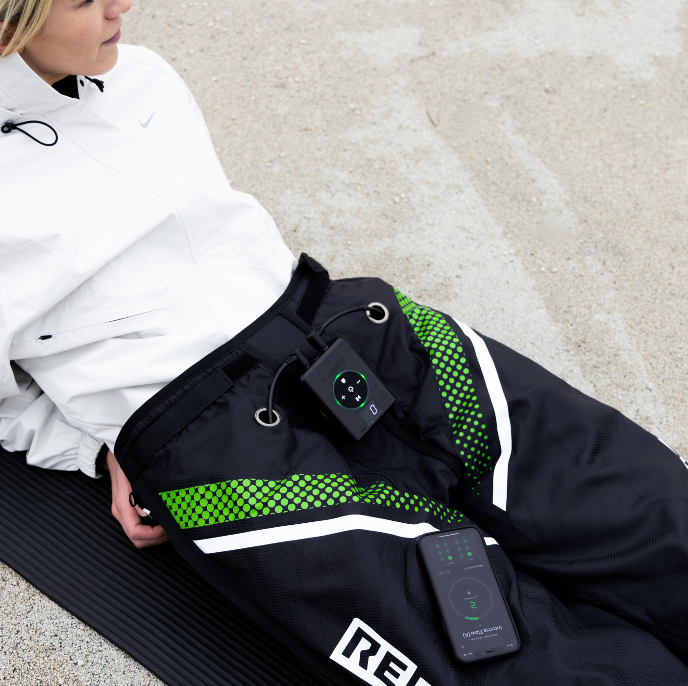 Reboots: Mujer sentada con chaqueta blanca, recuperando con la presoterapia deportiva GO X.