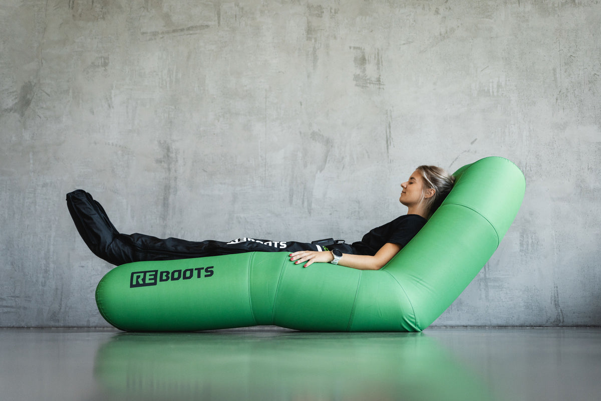 Mädchen sitzt auf einem grünen Sofa und macht eine Reboots Kompressionsmassage Sitzung.