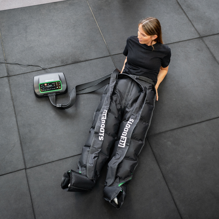 Reboots: Frau mit schwarzem T-Shirt, die sich mit einem One Lite Kompressionsmassage dehnt und erholt.