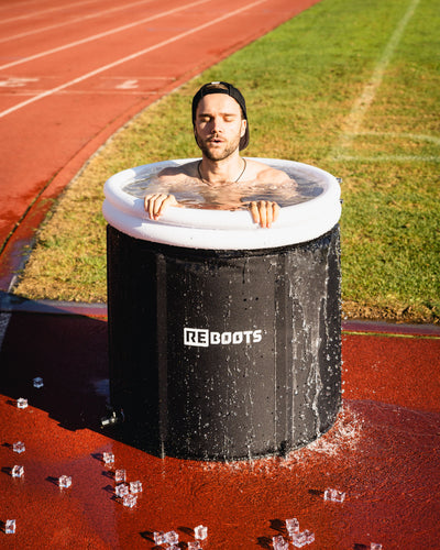 Sportler nimmt ein Kältebad im Reboots Ice Tub auf der Laufbahn – optimale Regeneration, Muskelkühlung und Erholung nach dem Sport.
