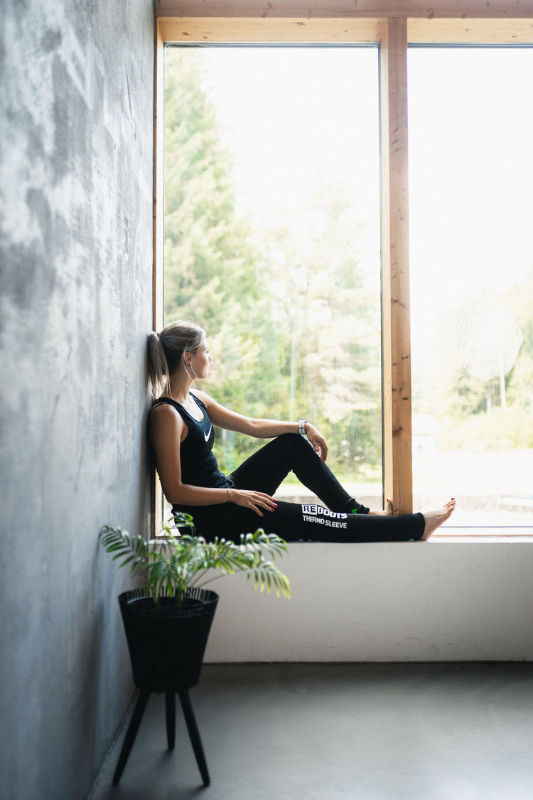 Reboots: Frau sitzt auf Fensterbank mit Thermosleeves an den Beinen