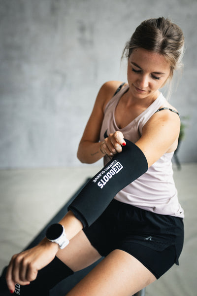 Frau nutzt den Reboots Thermo Sleeve zur gezielten Wärmetherapie am Arm für bessere Regeneration und Muskelentspannung nach dem Training.