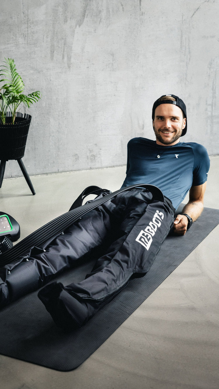 Sportlicher Mann nutzt das Reboots One Recovery System zur Beinregeneration nach dem Training – effektive Kompressionstherapie für schnellere Erholung der Muskulatur.