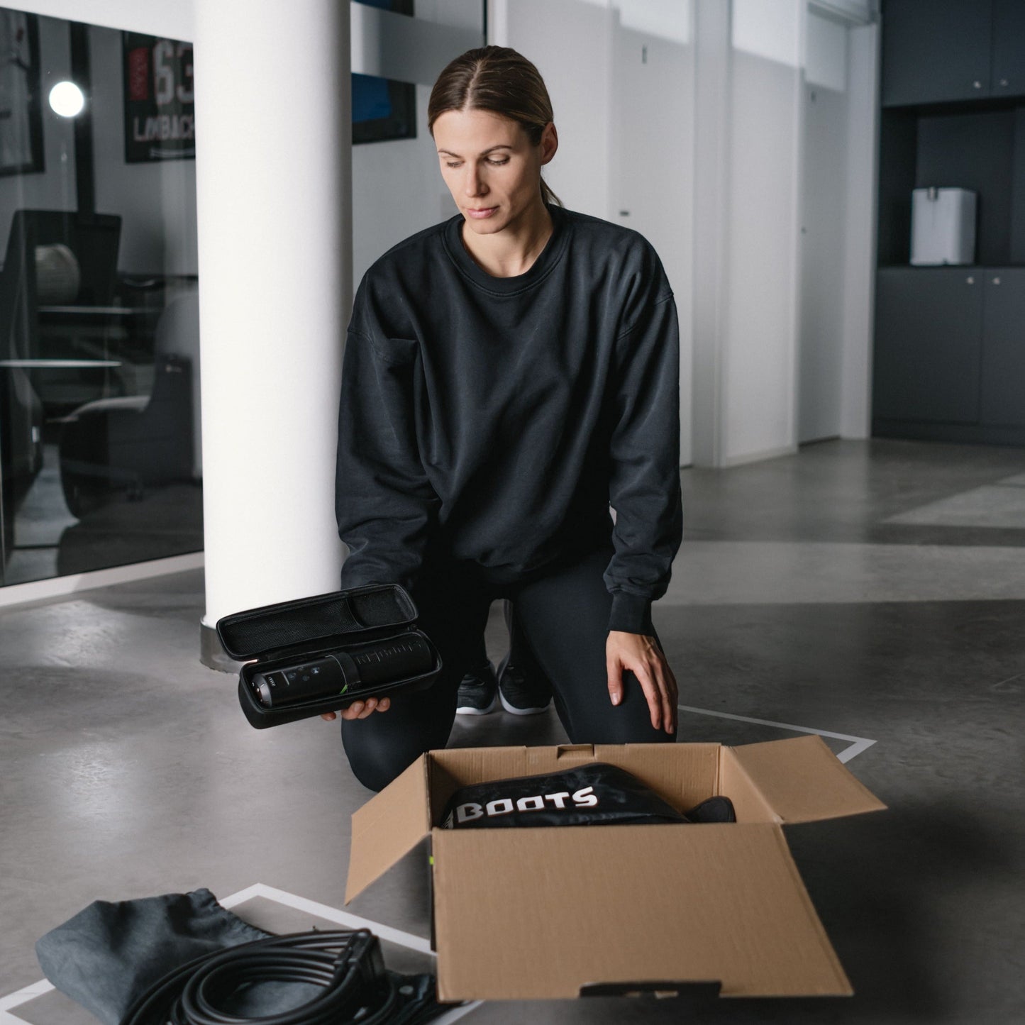Reboots: Frau kniet und öffnet eine Packung GO LITE Sport-Drucktherapie.