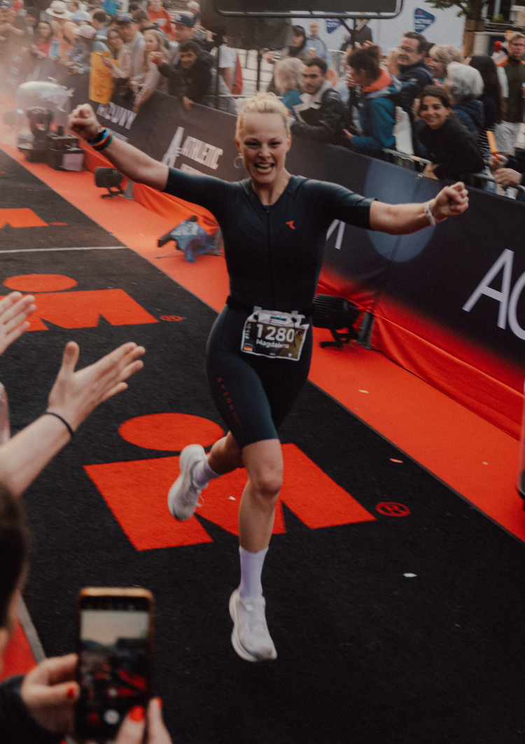 Athletin jubelt beim Zieleinlauf eines Ironman-Rennens – emotionaler Finish-Moment.