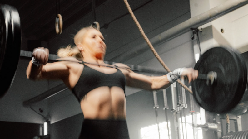 CrossFit-Athletin beim funktionellen Krafttraining mit Langhantel im Gym.