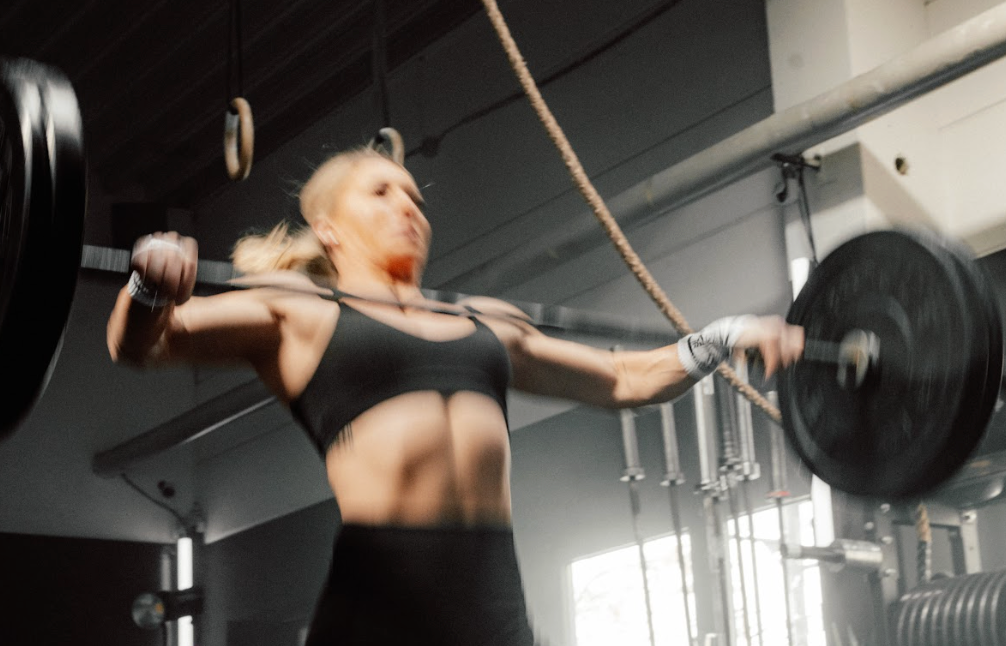 CrossFit-Athletin beim funktionellen Krafttraining mit Langhantel im Gym.