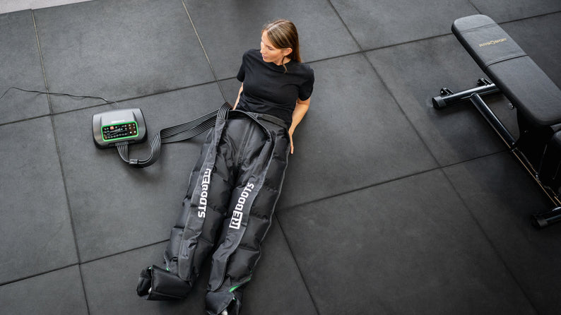 Reboots Kompressionsmassage für Beine im Fitnessstudio – Athletin nutzt Reboots Recovery Boots zur Regeneration nach dem Training, effektive Pressotherapie für Muskelentspannung