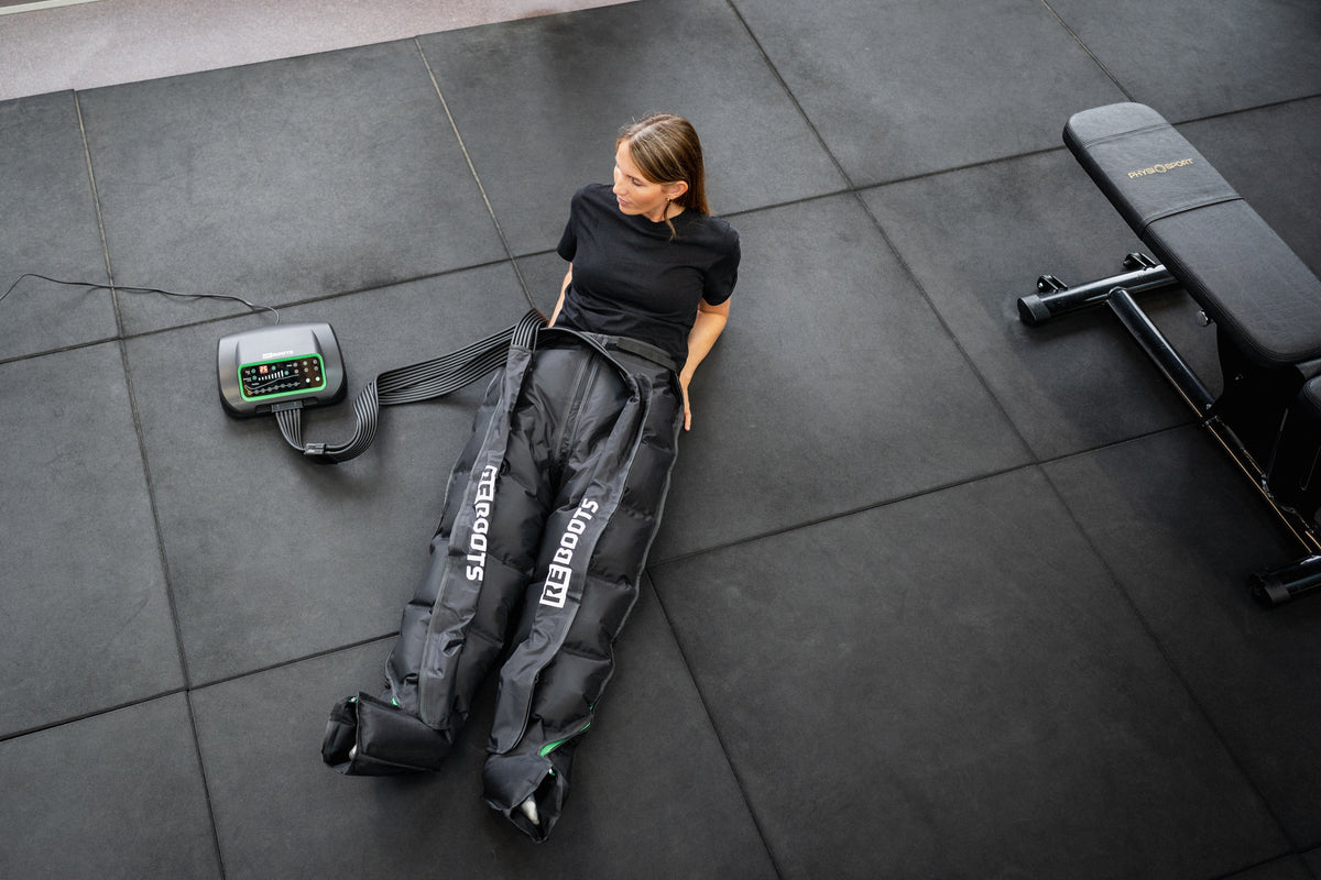 Reboots Kompressionsmassage für Beine im Fitnessstudio – Athletin nutzt Reboots Recovery Boots zur Regeneration nach dem Training, effektive Pressotherapie für Muskelentspannung