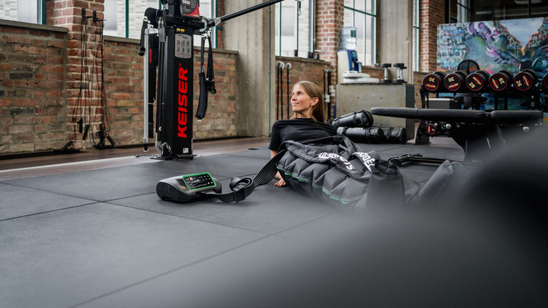 Frau nutzt Reboots Recovery Boots in einem Fitnessstudio.