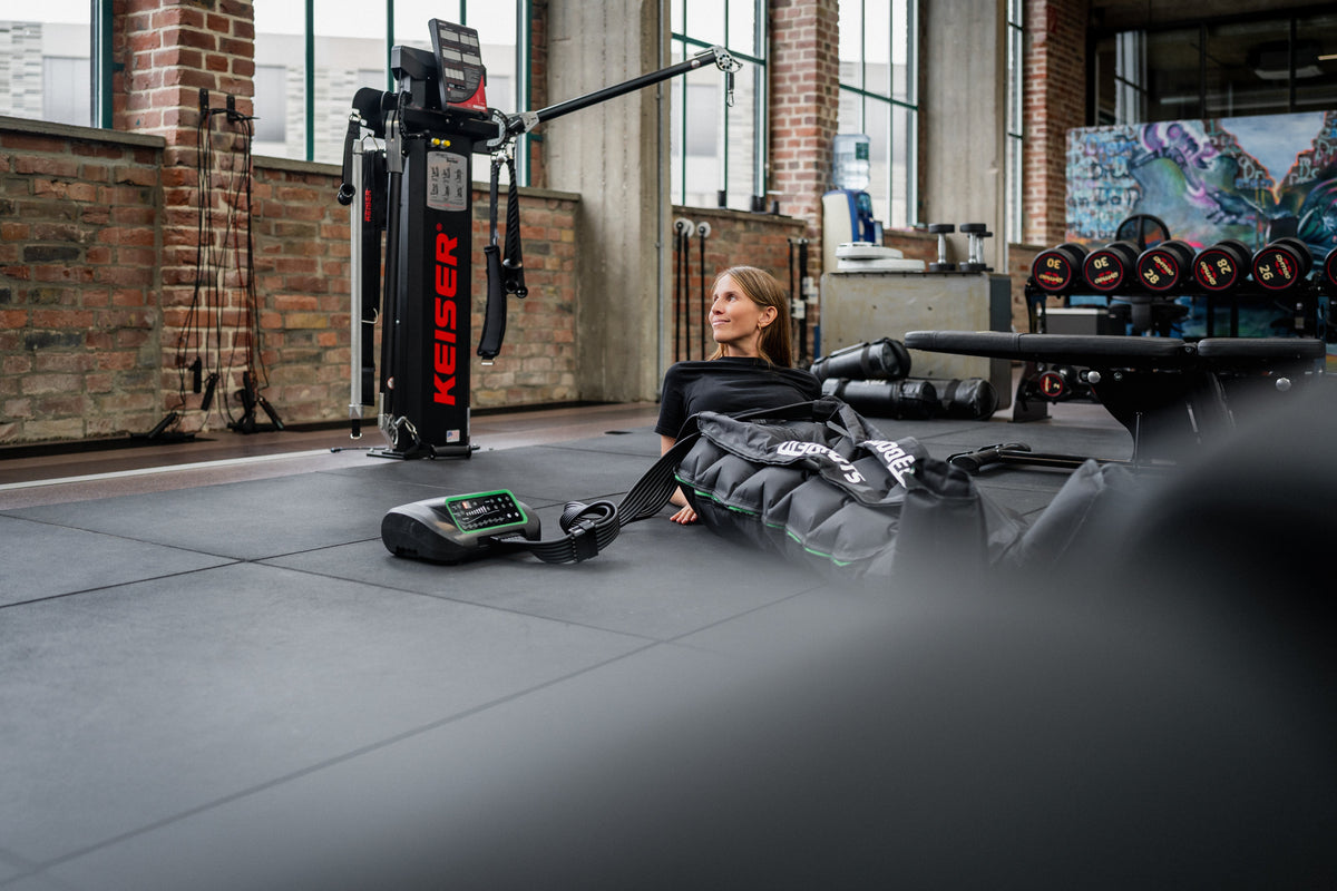 Frau nutzt Reboots Recovery Boots in einem Fitnessstudio.