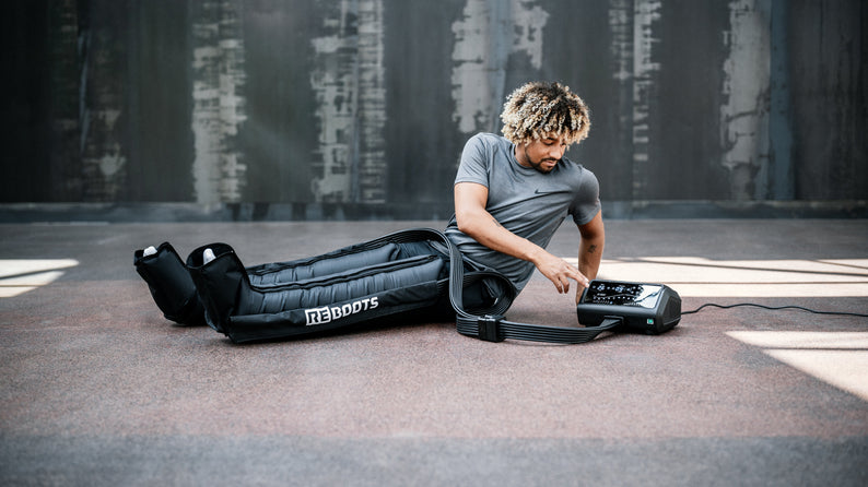 Sportler mit Reboots One Pro Recovery Boots bei der Anwendung – Kompressionsmassage für professionelle Regeneration im Sport.