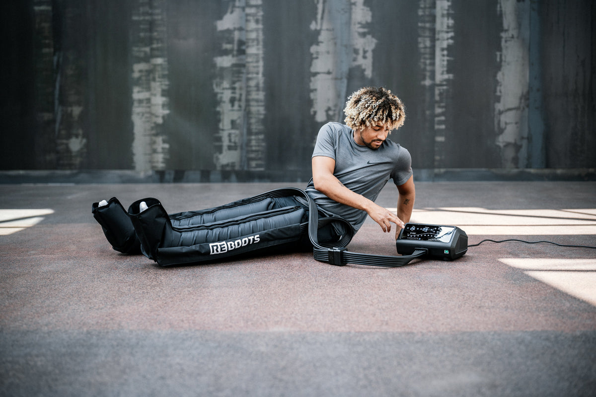 Sportler mit Reboots One Pro Recovery Boots bei der Anwendung – Kompressionsmassage für professionelle Regeneration im Sport.