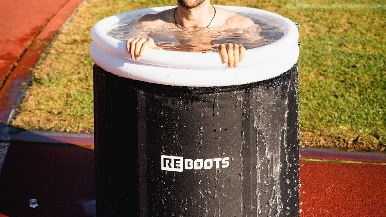 Sportler regeneriert nach dem Training in der Reboots Ice Tub mit Eiswasser auf der Laufbahn – optimale Kälteanwendung zur Muskelregeneration und Leistungssteigerung.
