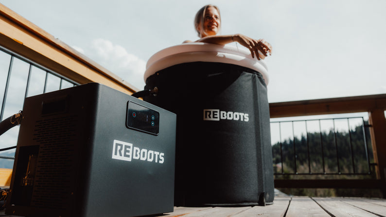 Frau genießt Kältebad im Reboots Ice Tub auf einer Sonnenterrasse – effektive Regeneration mit dem Reboots Ice Chiller für Muskelkühlung und Erholung nach dem Training.