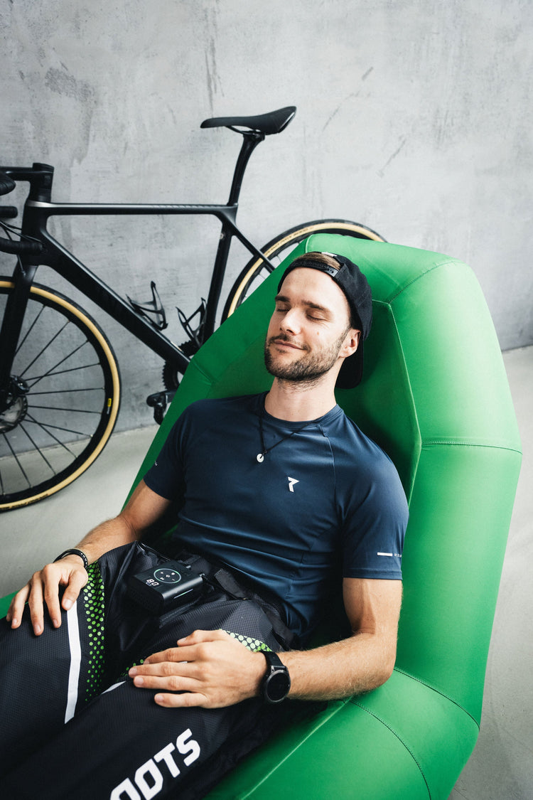 Athlet entspannt auf Liegesessel mit Reboots Recovery-Gerät nach dem Training.