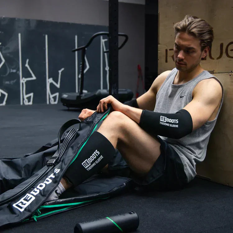 Athlet nutzt Reboots Thermo Sleeves und Recovery Boots zur Muskelregeneration im Fitnessstudio – effektive Wärme- und Kompressionsbehandlung für Arme und Beine