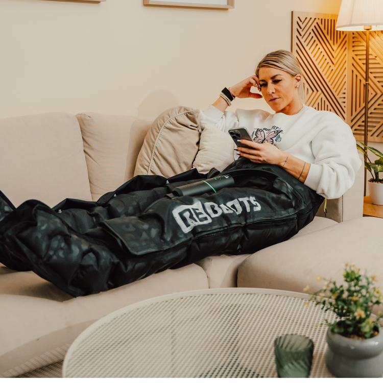 Sportlerin entspannt auf dem Sofa mit Reboots Recovery Boots Limited Edition im Leo Look zur Regeneration.