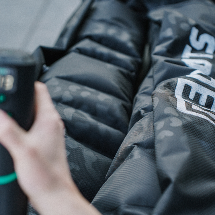 Detailaufnahme der Reboots Limited Edition Kompressionsboots im Leo Look mit mobilem Steuergerät während der Anwendung.