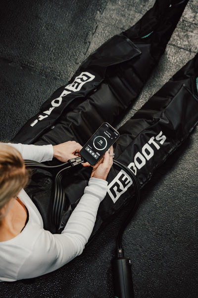 CrossFit-Athletin steuert die mobile Kompressionsmassage von Reboots per App im Fitnessstudio