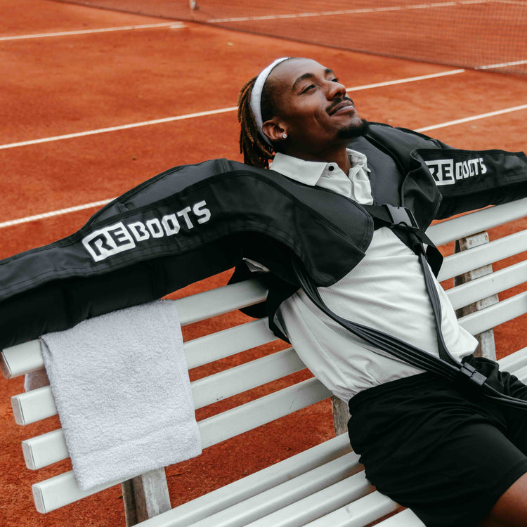 Reboots: Persona de color con camiseta blanca sentada y extendiendo los brazos.