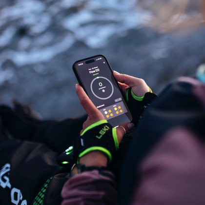 Sportlerin steuert ihre Reboots Recovery Boots über eine Smartphone-App in den Bergen – smarte Regeneration und Muskelentspannung nach intensiver Aktivität.