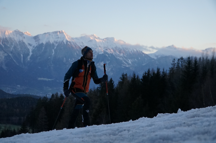 Sportler beim Wintertraining in den Bergen mit Sonnenaufgang – Ausdauertraining und aktive Regeneration im Schnee mit Fokus auf Reboots Recovery für bessere Leistungsfähigkeit.