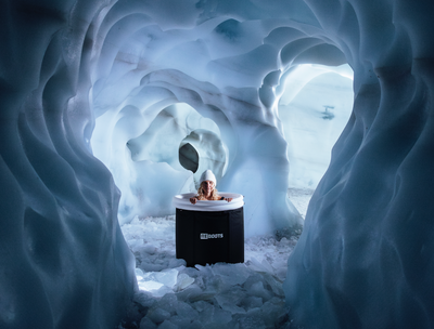 Person nimmt ein Eisbad im Reboots Ice Tub in einer beeindruckenden Eishöhle – Kältetherapie für Regeneration, Durchblutungsförderung und Muskelentspannung nach dem Sport.