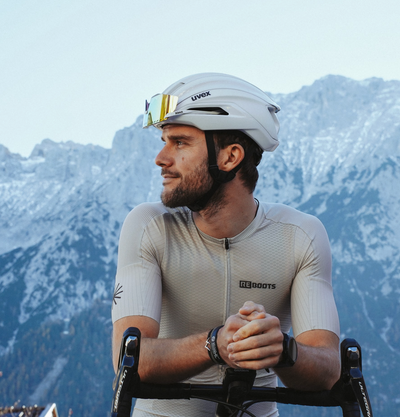 Radsportler mit Reboots Bike Jersey aus der Move & Recover Collection vor alpiner Bergkulisse auf dem Rennrad.