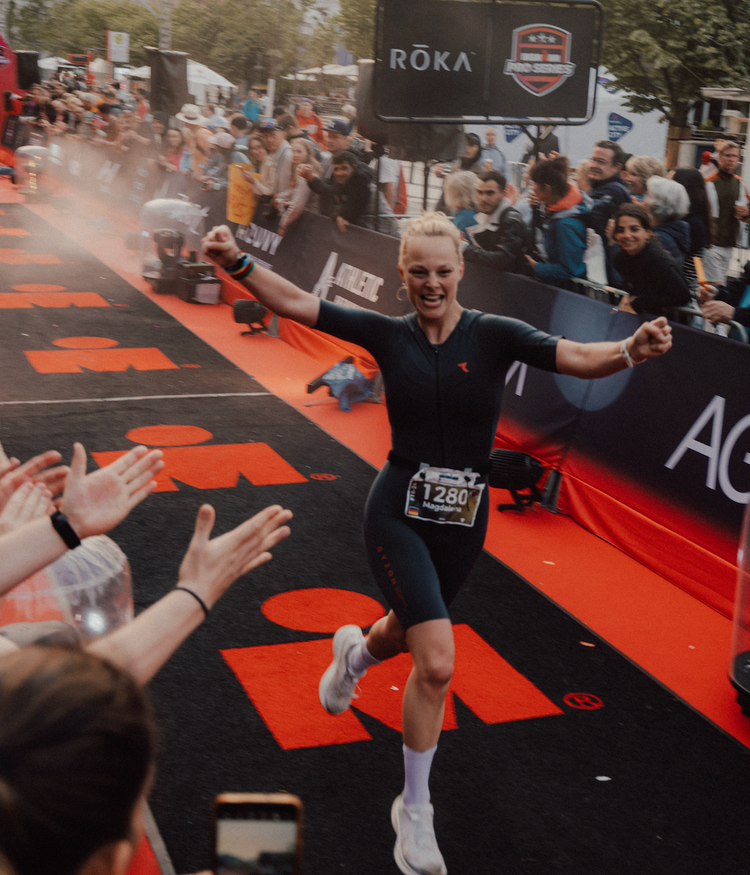 Ironman Finisherin jubelt beim Zieleinlauf eines Triathlons – dynamischer Moment.
