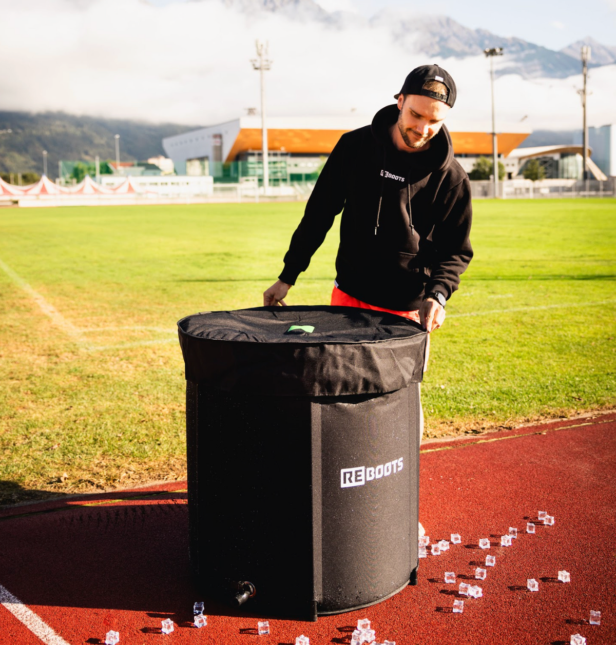 Reboots Ice Tub auf der Laufbahn – mobiles Eisbad zur Kälte-Regeneration nach dem Training im Stadion. Mann deckt das ice Tub ab. 