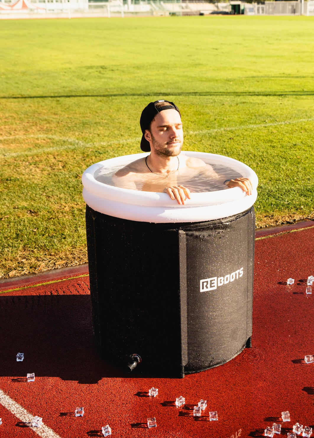 Sportler im Reboots Ice Tub auf der Laufbahn – Eisbaden zur Kältetherapie und schnelleren Muskelregeneration nach intensivem Training im Freien.