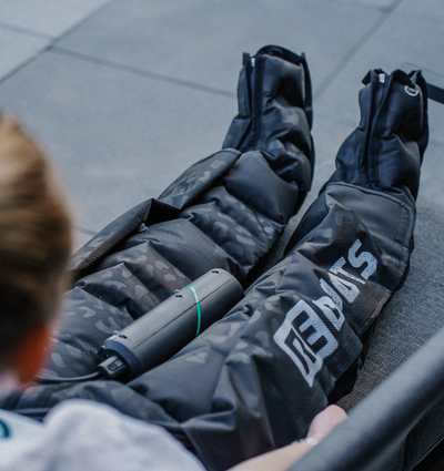 Detailaufnahme der Reboots Limited Edition Kompressionsboots im Leo Look mit mobilem Steuergerät während der Anwendung.