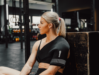 Sportlerin nutzt Reboots Shoulder Thermo Sleeve im Gym. 