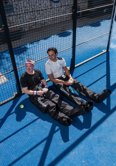 Zwei Padel-Spieler mit Reboots Kompressionsmassage bei der Regeneration auf dem Padel-Court