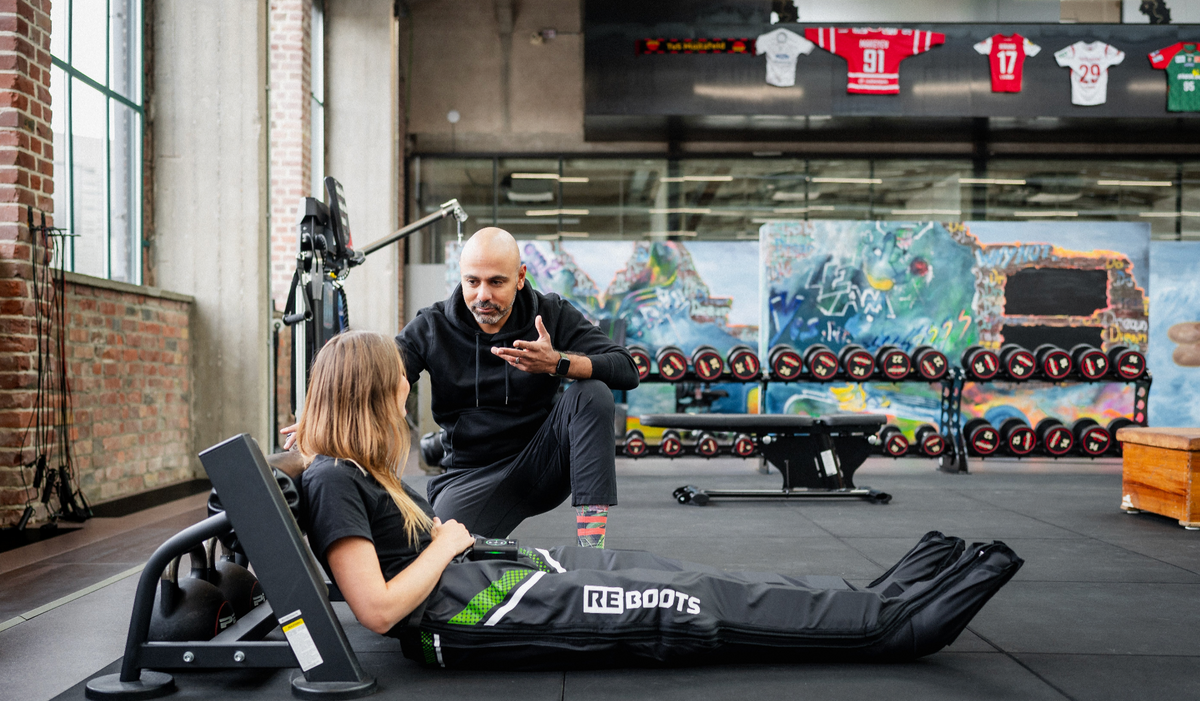 Reboots Go X Beratungsgespräch mit Trainer während der Recovery-Anwendung im Fitnessstudio