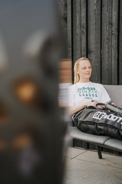 Sportlerin nutzt Reboots Limited Edition Kompressionsboots im Leo Look zur Regeneration der Beine nach dem Training.