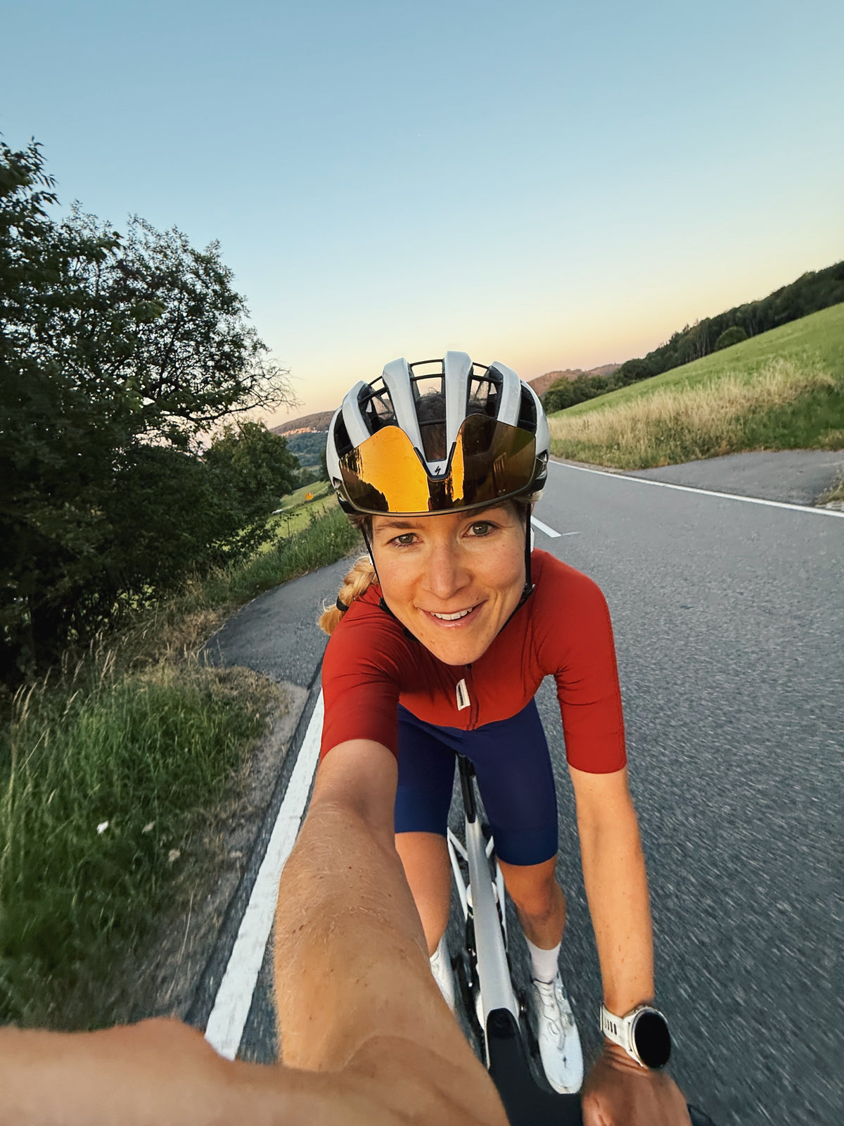 Athlete Project Teilnehmerin Catherine Rossmann während einer Radausfahrt auf der Strecke des Ötztaler Radmarathons, Selfie-Perspektive bei Sonnenuntergang.