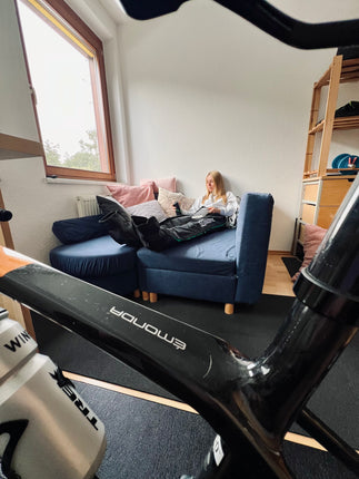 Reboots: Frau entspannt mit Beinkompressionsmassage auf Sofa