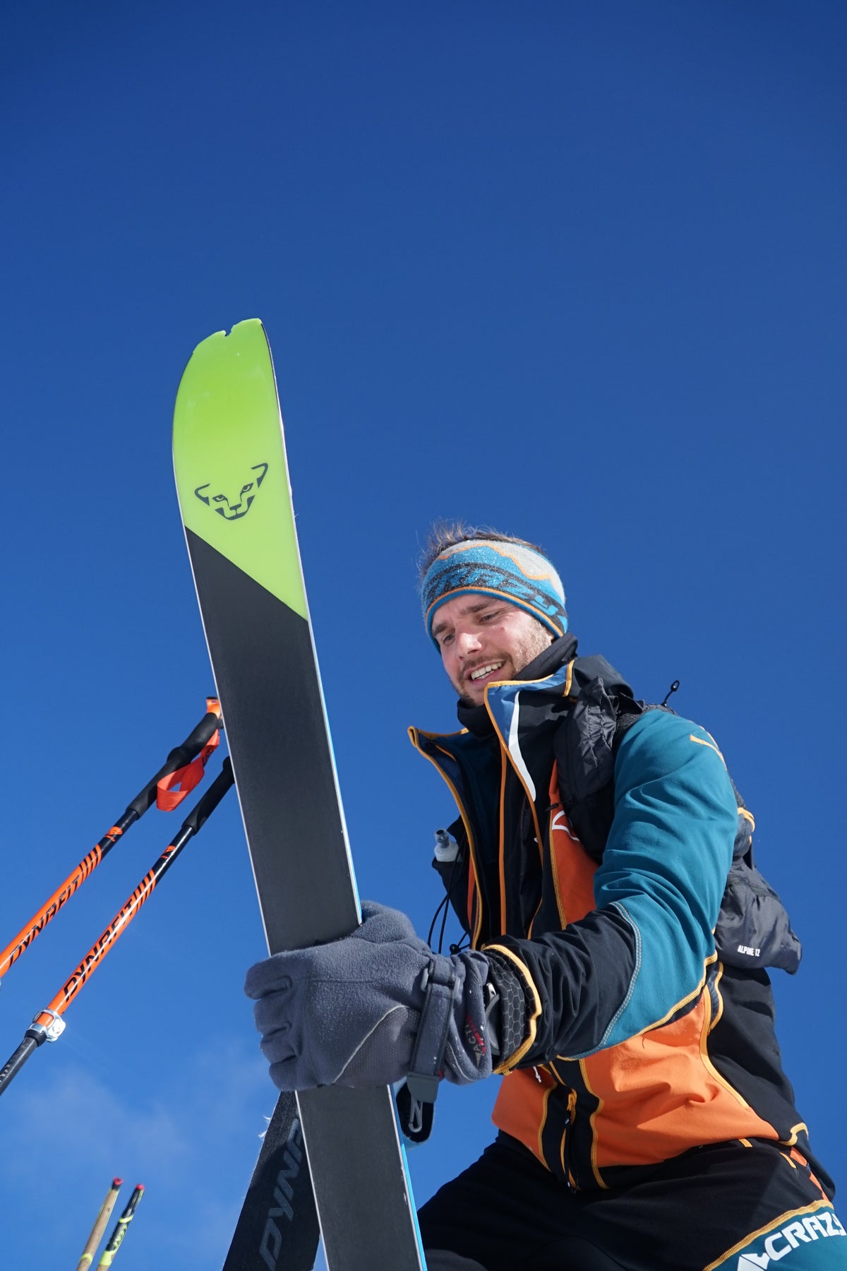 Skibergsteiger bereitet seine Ausrüstung am Gipfel vor – Wintersport und Regeneration im Hochgebirge unterstützt durch Reboots Recovery für optimale Muskelentspannung.
