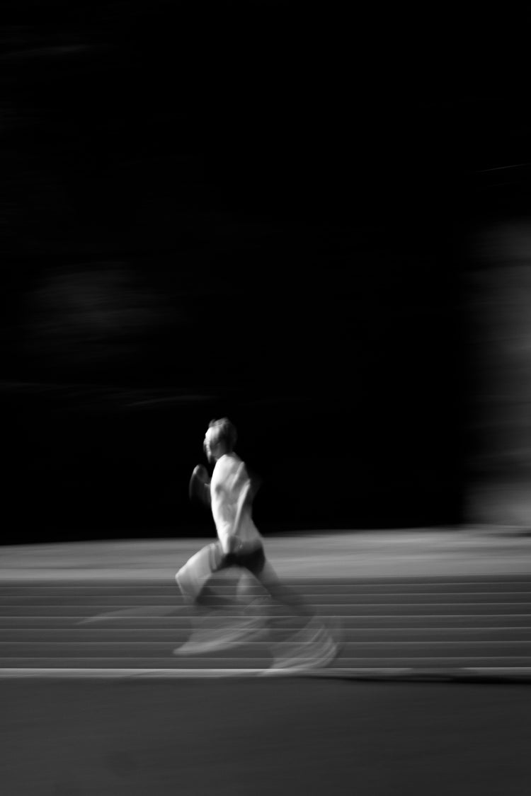 Schwarz-Weiß-Porträt eines Läufers im Intervalltraining – Fokus, Schnelligkeit und Ausdauer im Leistungssport.