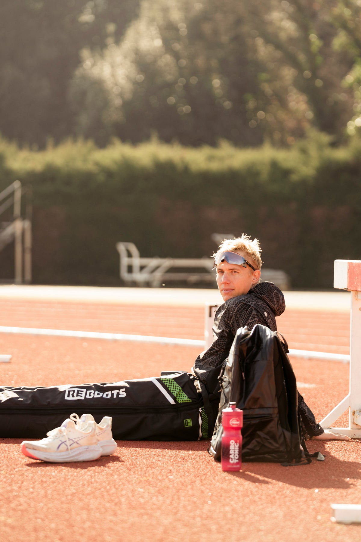Triathlet entspannt nach dem Training auf der Laufbahn mit Reboots Kompressionsmassage Boots zur schnellen Regeneration der Beine.