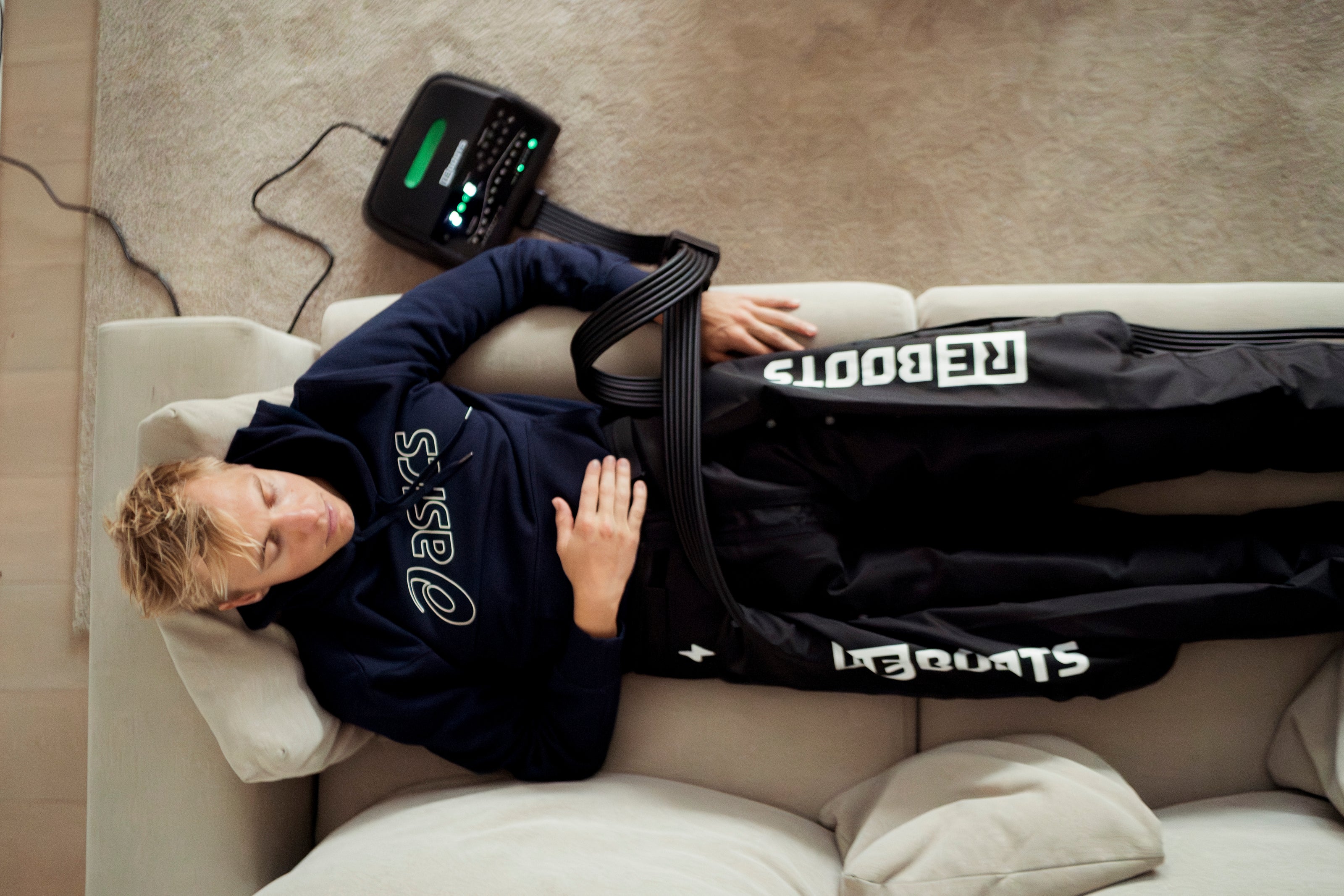 Jonas Schomburg regeneriert mit der Reboots One Pro Kompressionsmassage auf dem Sofa