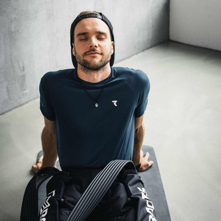 Reboots: Eine Person sitzt auf einer Matte und erholt sich zu Hause mit entspanntem Gesichtsausdruck.