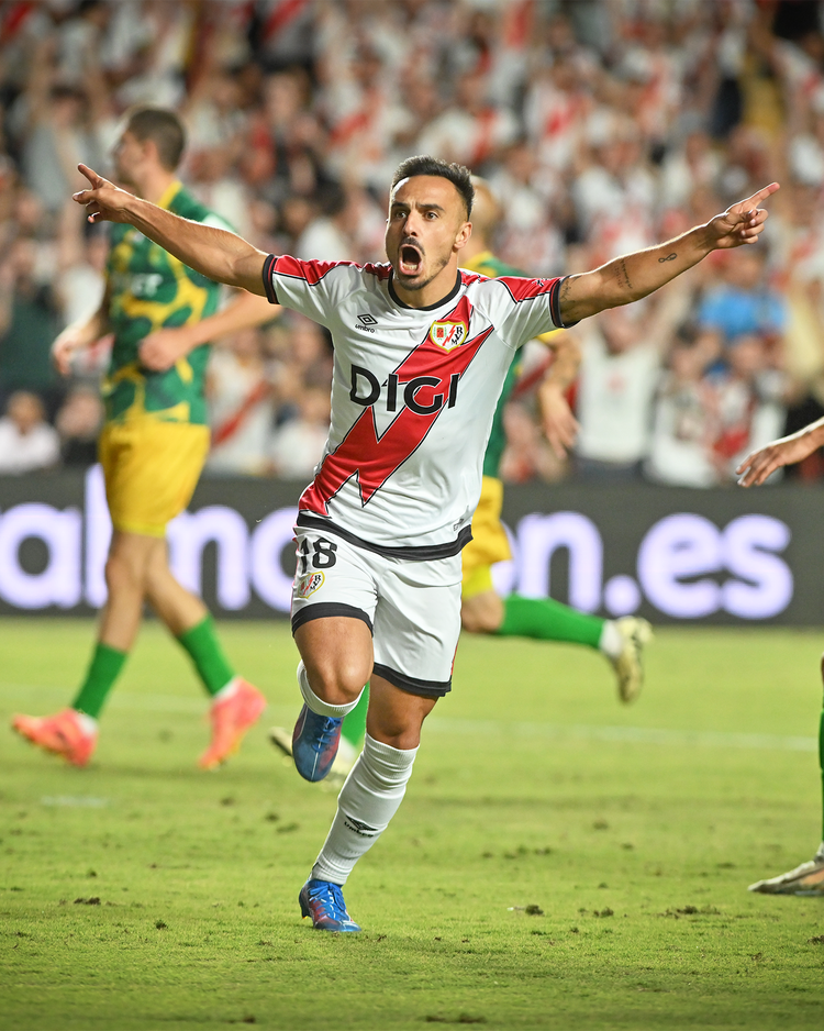 Fußballspieler von Rayo Vallecano jubelt nach einem Tor während eines Ligaspiels; dynamische Szene vor jubelnden Fans.