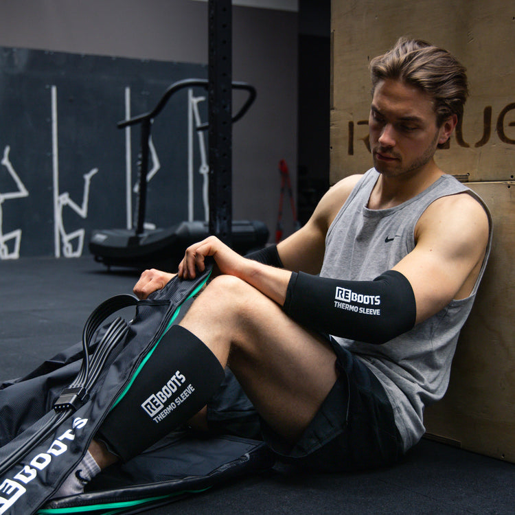 Reboots: Person, die in einem Fitnessstudio sitzt und sich mit Sport-Drucktherapie und Thermomanschetten erholt.