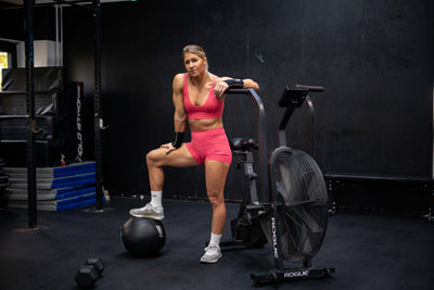 Hyrox-Athletin posiert am Airbike im Fitnessstudio