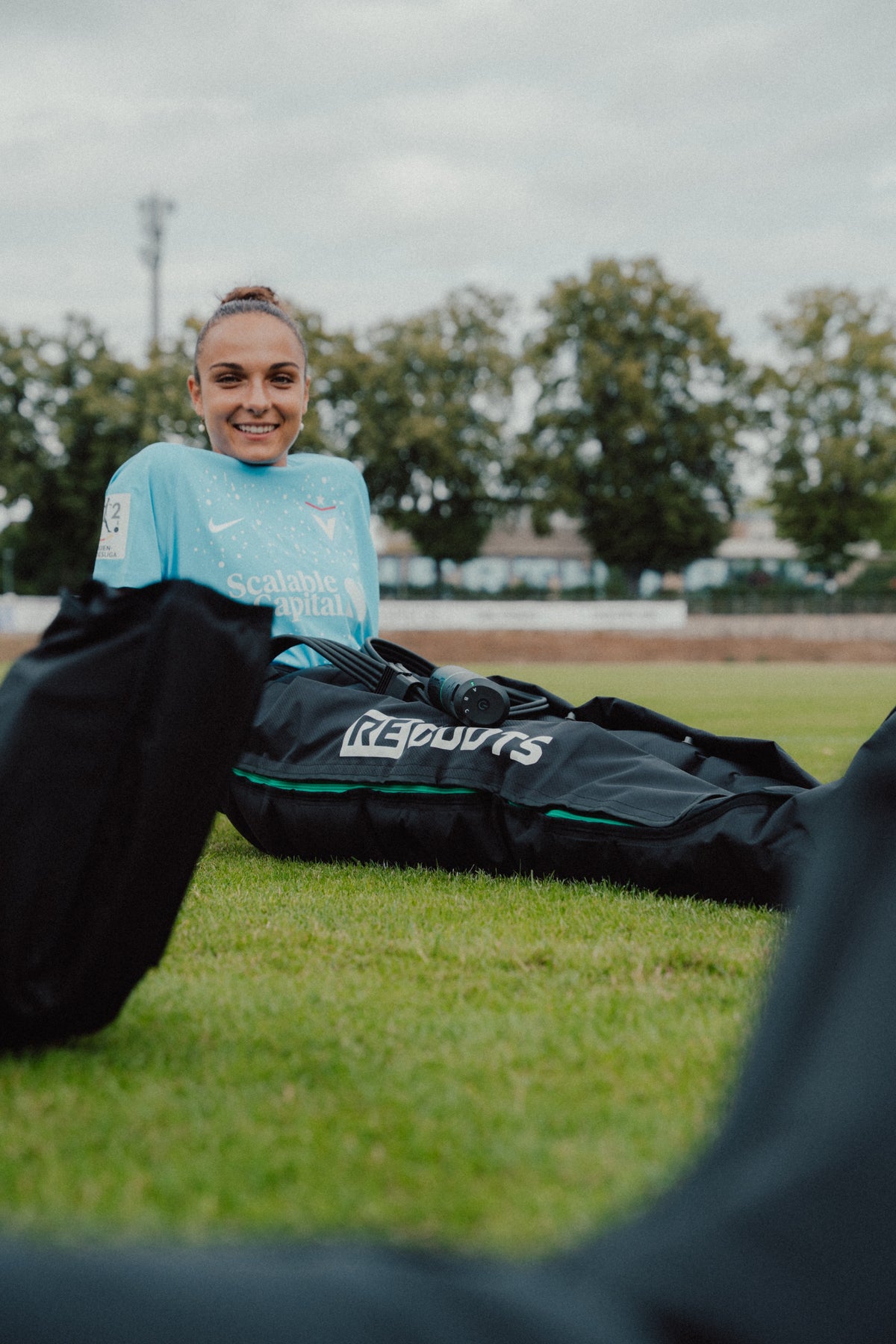 Reboots Go X Kompressionsboots auf dem Fußballplatz – Fußballerin Katharina Krist nach dem Training mit Recovery-Tasche