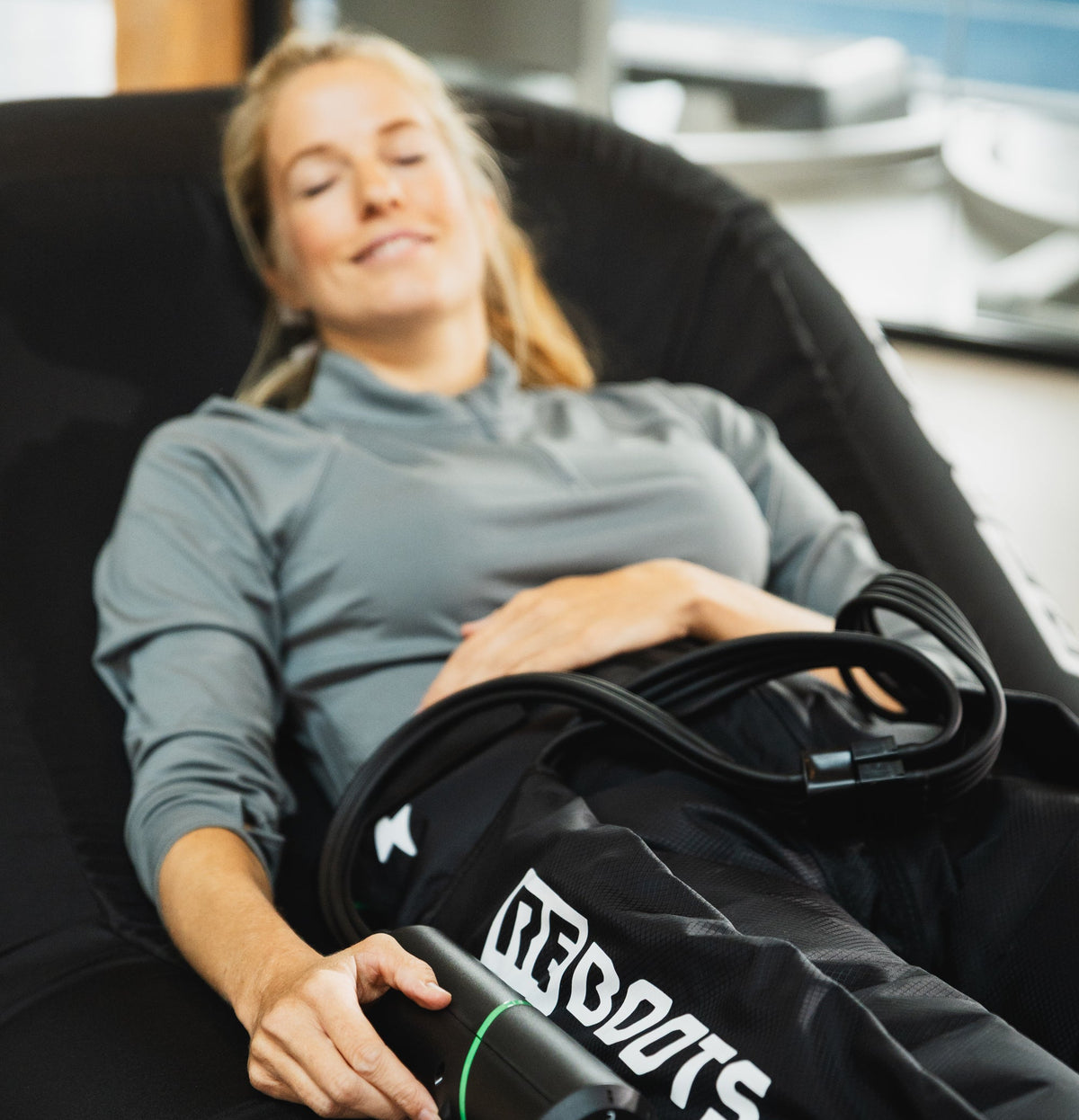 Reboots Kompressionsmassage für Beine im Fitnessstudio – entspannte Regeneration nach dem Training mit mobilem, kabellosem Steuergerät.